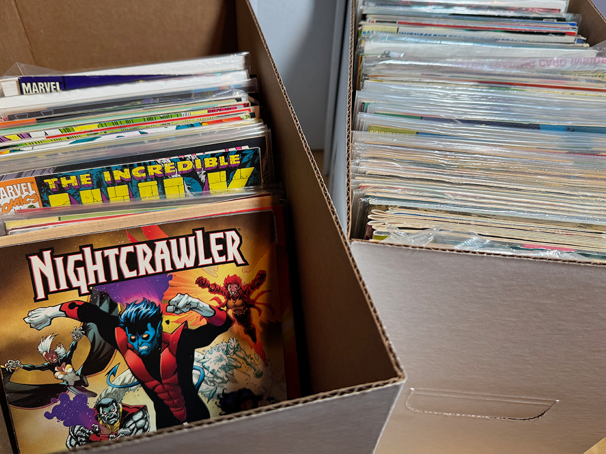 A cardboard box of unsorted comic books — Incredible Hulk #181 and a Nightcrawler issue visible on top of the stack, with another box behind it full of comics.
